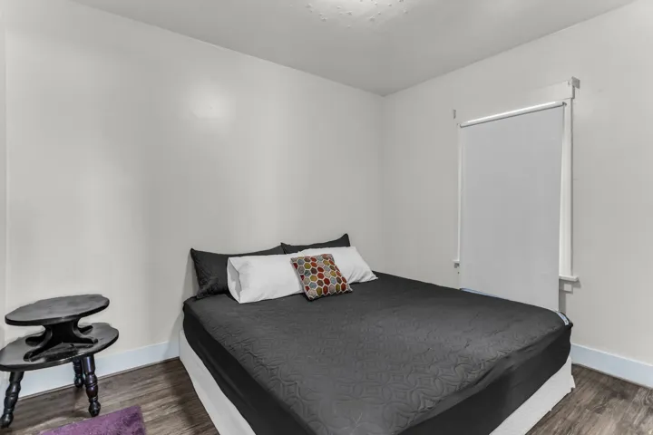 Wood-finish flooring with crisp white baseboards, neutral wall tones, and a window with a roller shade