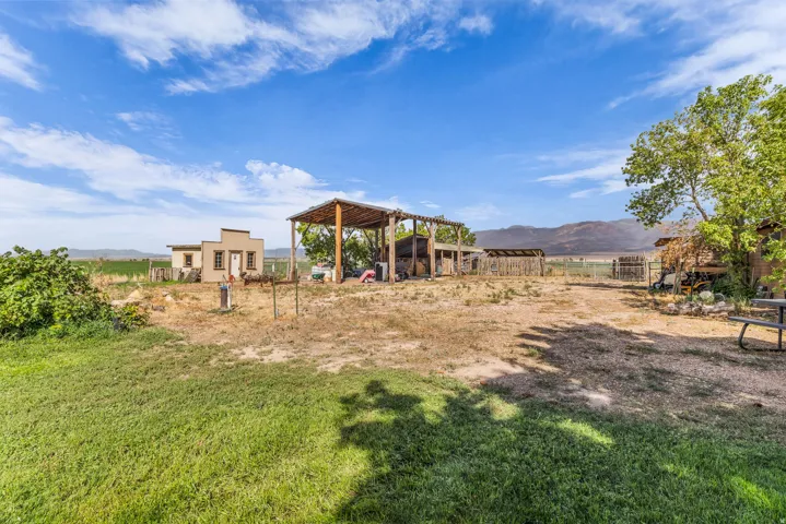 Expansive outdoor space featuring a covered wood structure, additional outbuildings, and a partial grass lawn