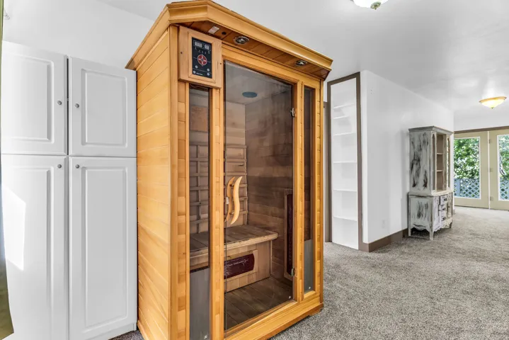 Built-in sauna with wood and glass construction, accompanied by white built-in cabinetry and recessed shelving