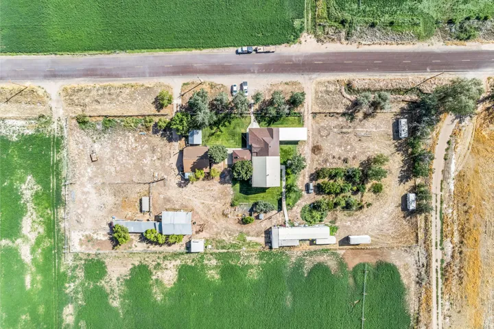 Expansive property featuring a central residence with a gabled roof, multiple outbuildings, and surrounding agricultural fields