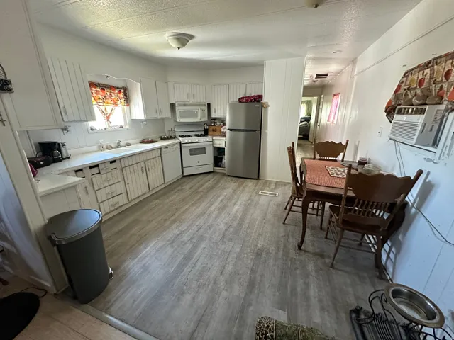 Kitchen featuring wood-finish flooring, white cabinetry, a double basin sink, and a white gas range