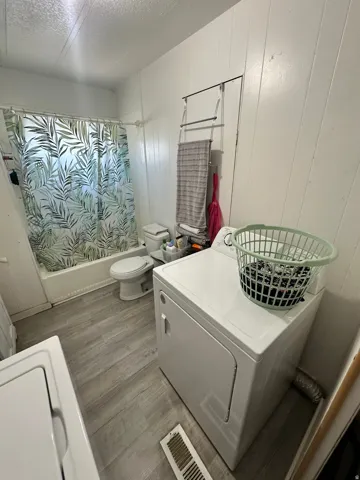 Tub and shower combination, toilet, and wood-finish flooring