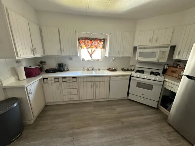 White cabinetry and countertops with wood-finish flooring