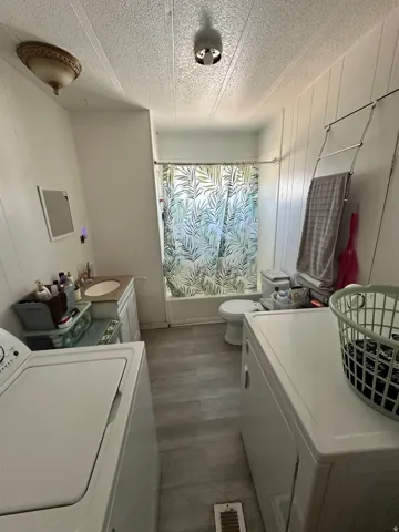 Full bathroom with a built-in tub and shower, single vanity, and wood-finish flooring