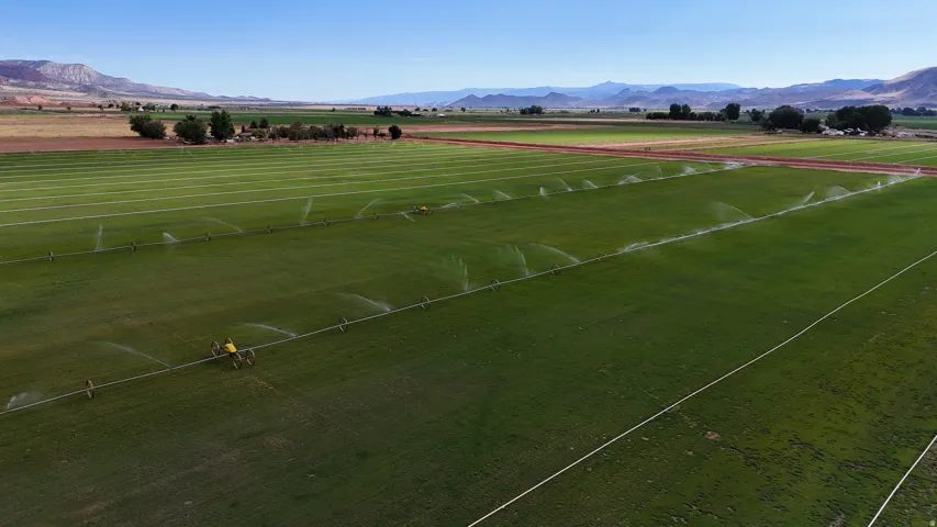 Expansive agricultural land featuring a robust irrigation system, verdant fields, and distant mountain ranges