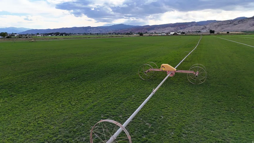 Expansive green field with a linear irrigation system and distant mountain scenery