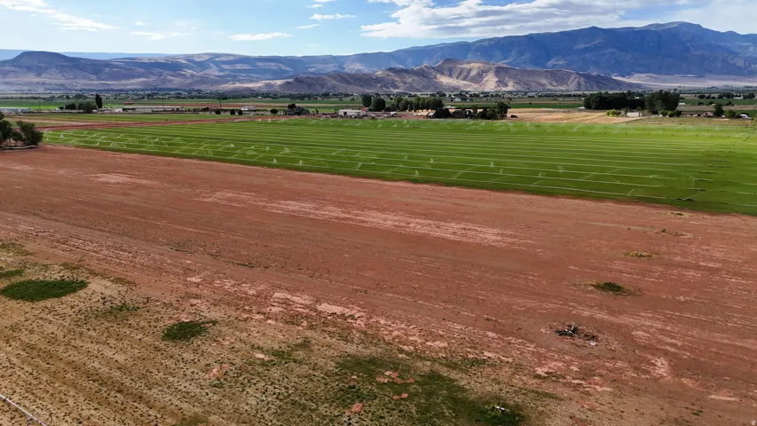 Expansive open fields with active irrigation systems, set against a backdrop of distant mountains