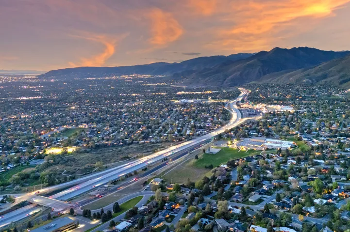 Expansive residential area with a prominent highway, illuminated cityscape, and distant mountain range
