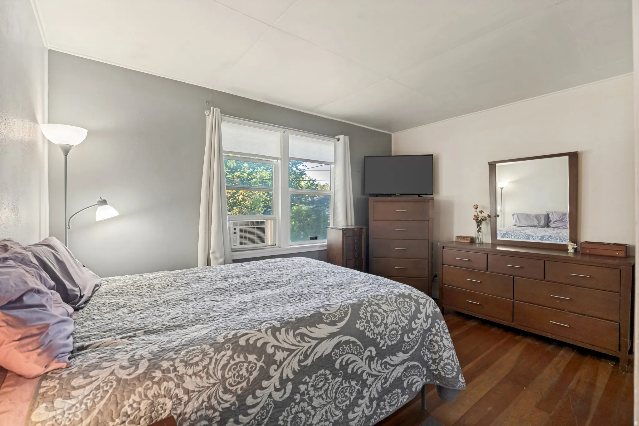 Hardwood flooring, painted walls, white trim, and a window with an air conditioning unit