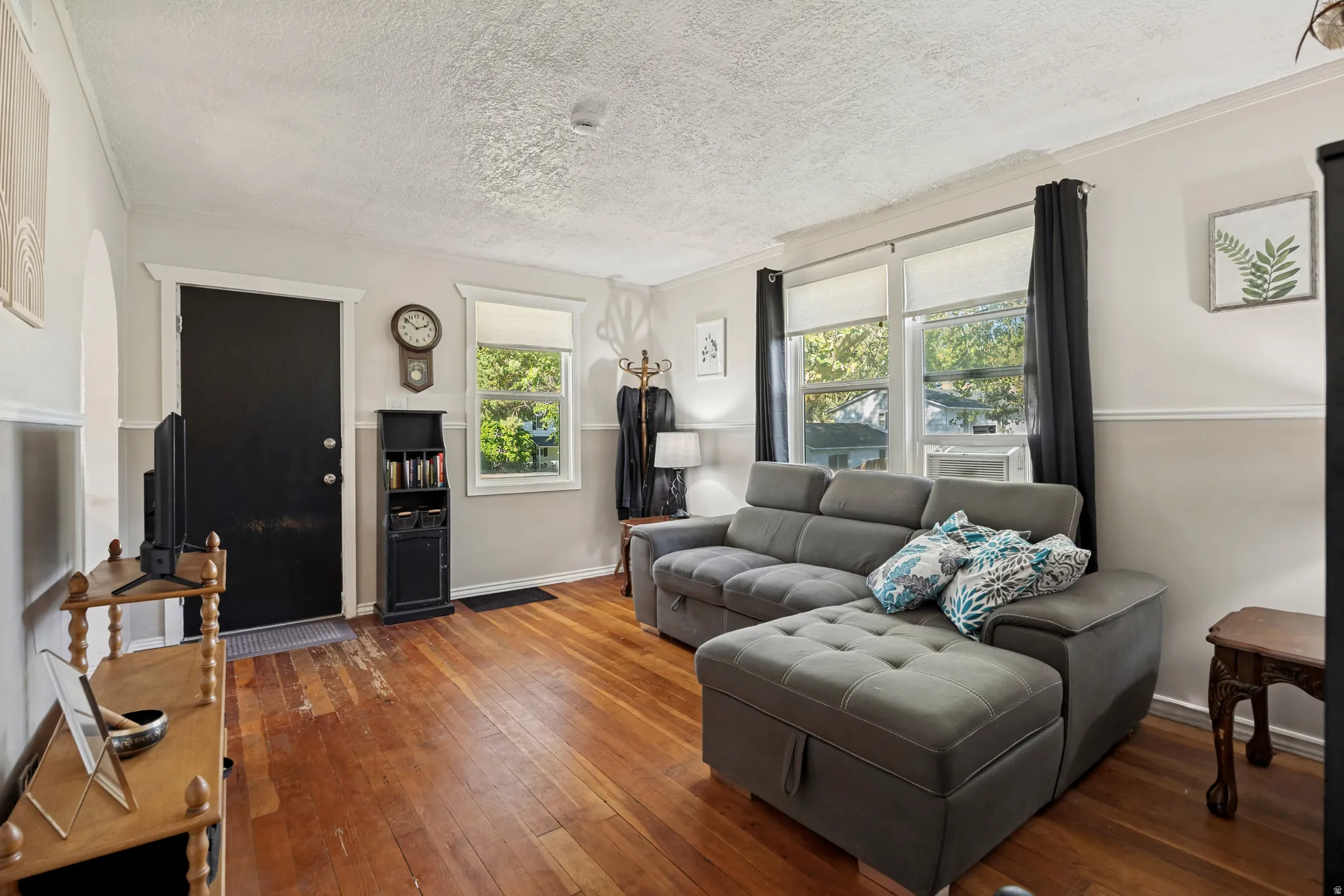 Hardwood flooring, painted interior walls, multiple windows with natural light, white trim, and a prominent entry door