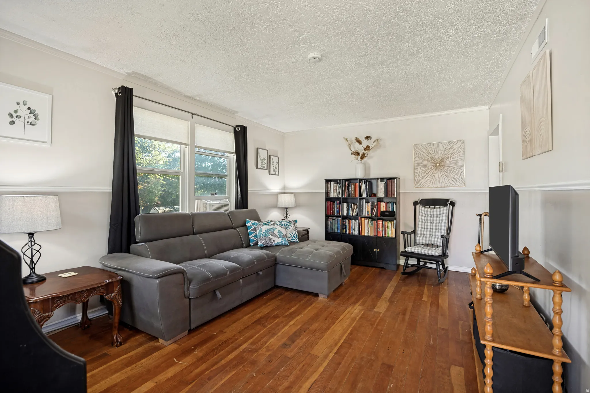 Hardwood flooring, white wall paneling, crown molding, and dual windows
