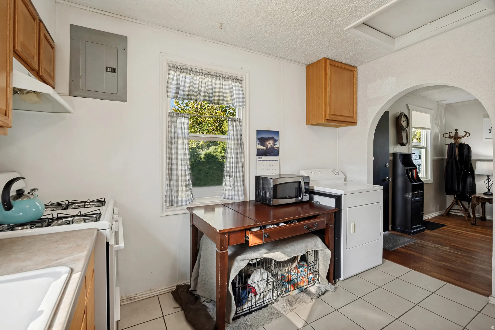 Kitchen area featuring tile flooring, wood cabinetry, a gas range, and a window with exterior views