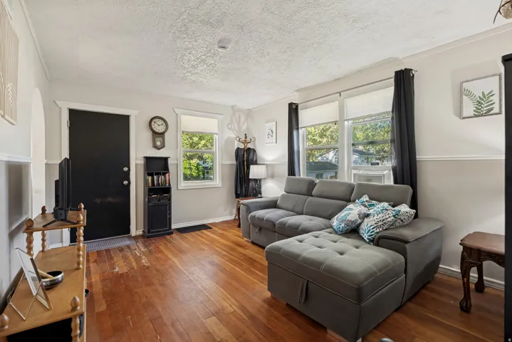 Hardwood flooring, painted interior walls, multiple windows with natural light, white trim, and a prominent entry door