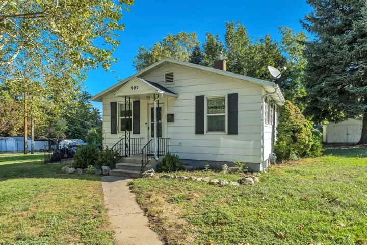 White siding exterior with black window shutters and a covered entry