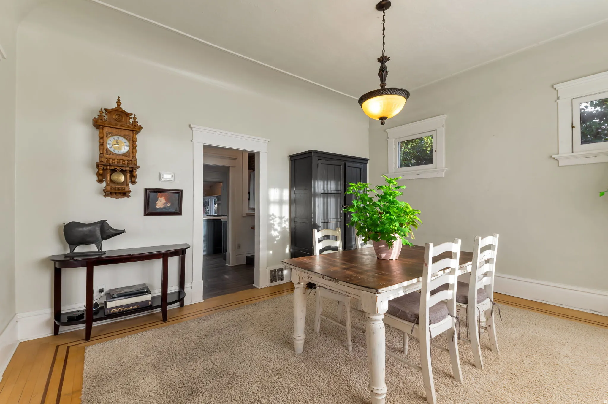 Hardwood flooring with border inlay, white trim throughout, and a hanging light fixture