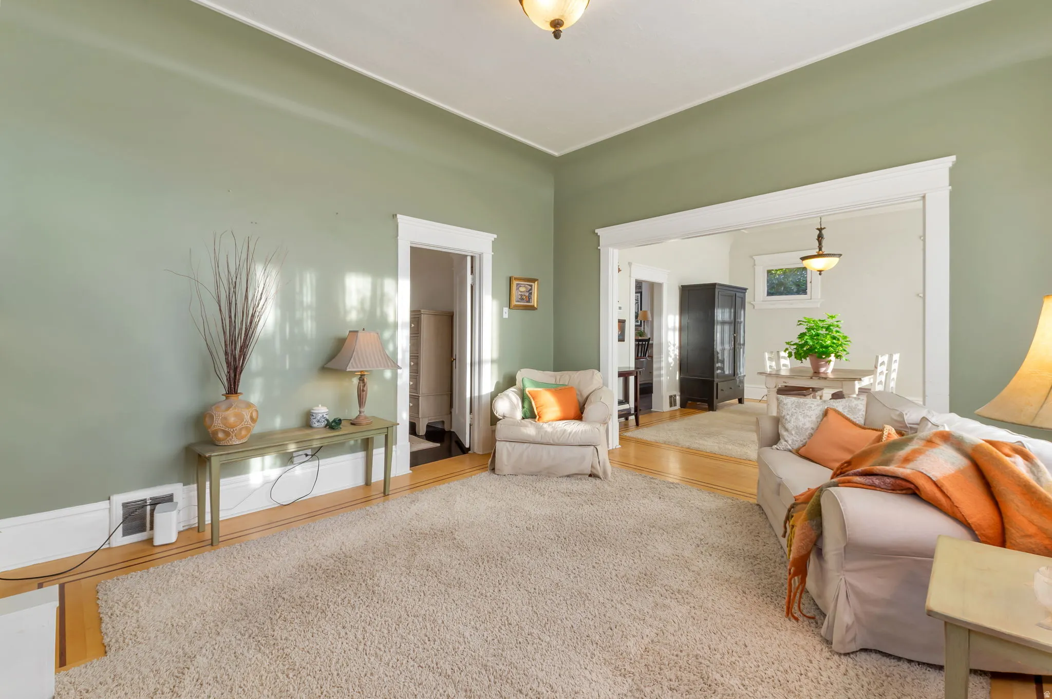 Hardwood flooring, broad room openings, decorative trim, and an overhead light fixture