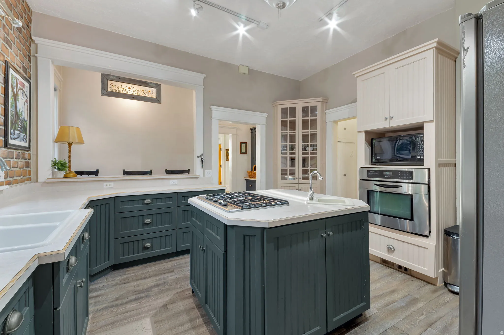 Kitchen featuring a central island with a built-in gas cooktop, dual-tone cabinetry, wood-finish flooring, and integrated stainless steel appliances