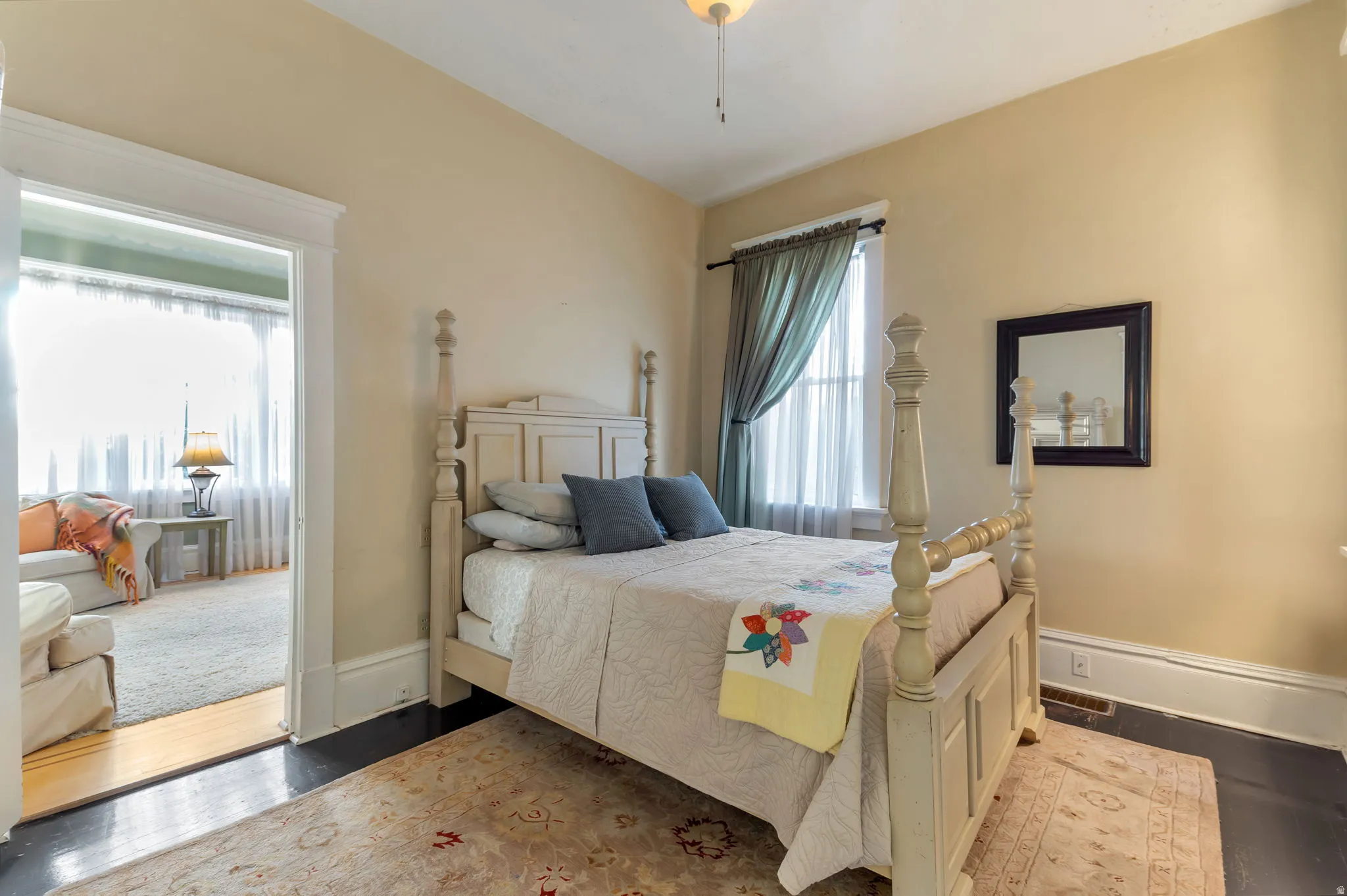 Hardwood flooring with an area rug, a window with drapery, and a ceiling fan