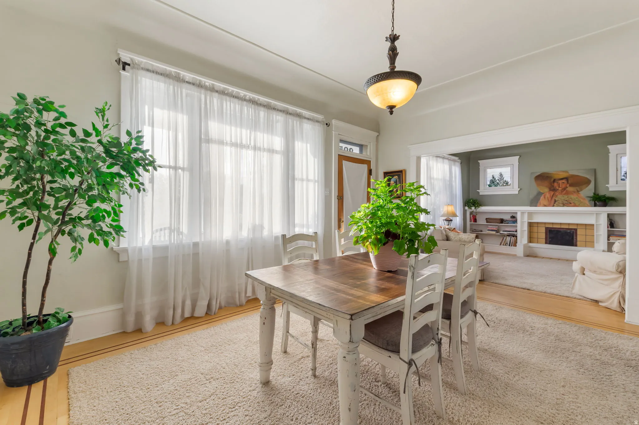 Hardwood flooring with border inlay, overhead chandelier lighting, and a wide cased opening to an additional room