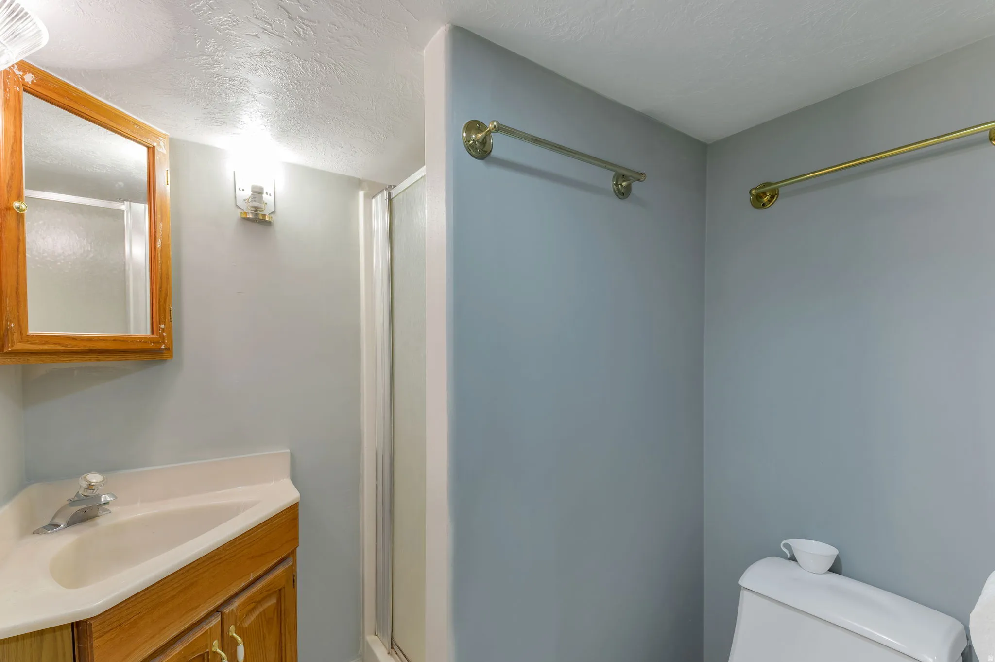 Corner vanity with wood-finish cabinetry, integrated sink, and chrome faucet