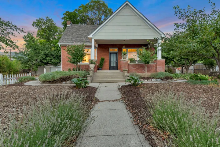 Brick exterior with a covered porch, white pillars, and a gabled roofline