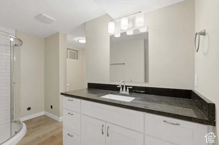 White vanity with a dark countertop, undermount sink, and chrome faucet