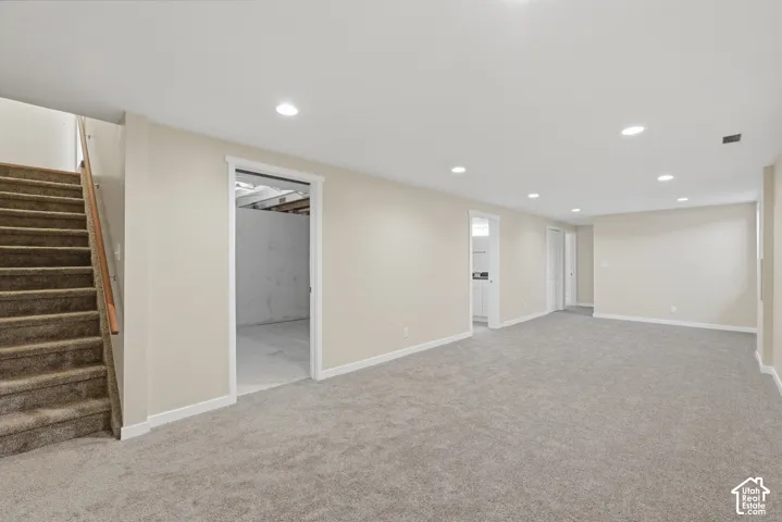 Expansive carpeted area with recessed lighting, light-toned walls, and white trim