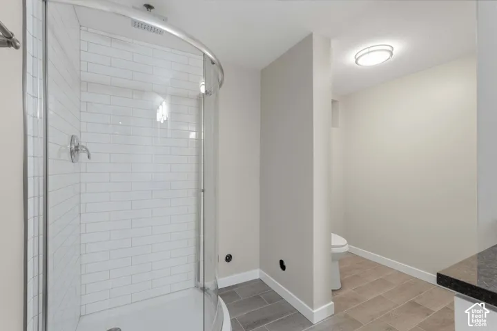 Curved glass shower enclosure with white subway tile, chrome fixtures, and a white shower pan