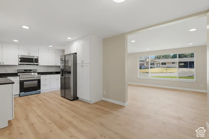 White shaker cabinetry, dark countertops, and stainless steel appliances