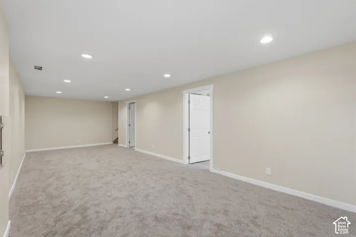 Expansive finished room with recessed lighting, neutral wall paint, and gray carpet flooring