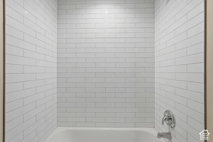 White subway tile surround, polished chrome fixtures, and a white bathtub