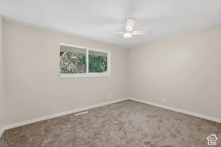 Neutral tone walls with white trim, brown carpet, and a ceiling fan with integrated lighting