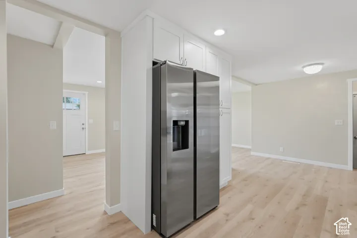 White cabinetry, stainless steel refrigerator, wood-finish flooring, recessed lighting, and a flush mount ceiling fixture