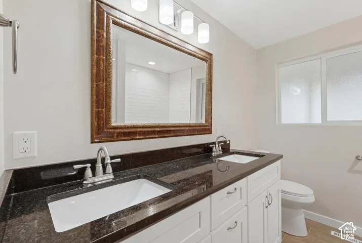 Double vanity with dark countertop, dual undermount sinks, and chrome faucets