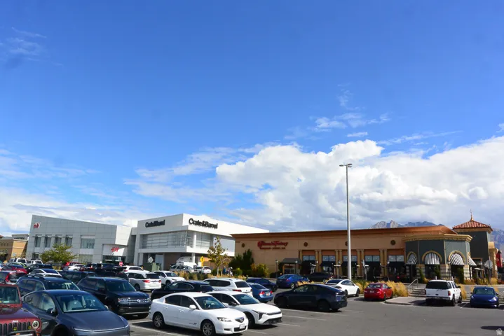 Expansive parking area with multiple retail establishments and mountain scenery
