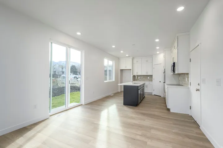 Open-concept living space featuring wood-finish flooring, recessed lighting, and a kitchen with white cabinetry