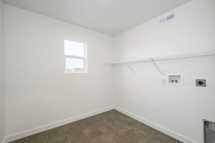 Rectangular window, white wire shelving, wall-mounted outlets, durable tile flooring
