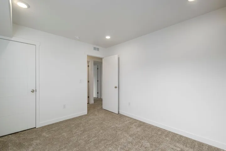 Recessed lighting, white walls, textured carpeting, and white interior doors