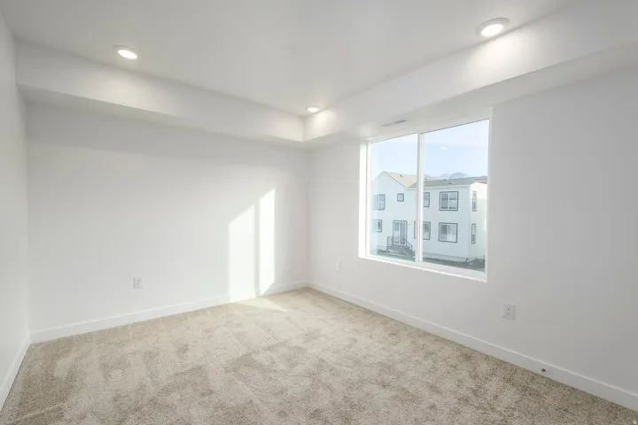 Recessed lighting, large window, neutral carpet, white walls, and white trim
