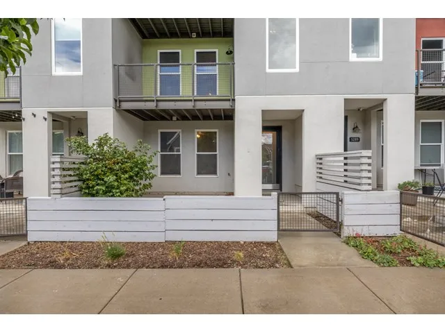 Modern facade with multiple balconies, a gated front entry, and contemporary windows