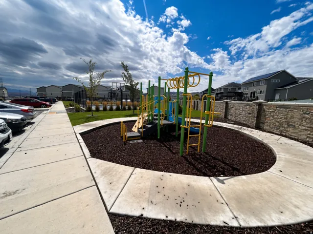 Outdoor recreation area featuring a playground with a slide and climbing elements, surrounded by a wood chip surface