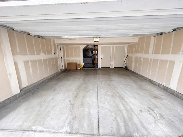 Two-car garage with concrete flooring, neutral-toned walls, and a ceiling-mounted light fixture