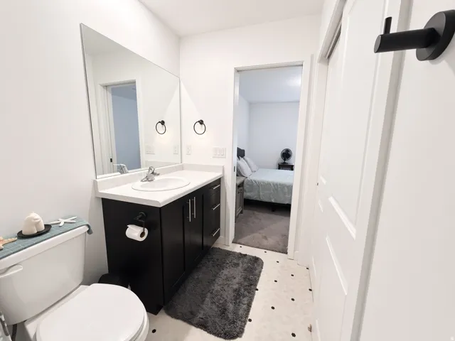 Vanity with a single basin sink, white countertop, and dark cabinetry