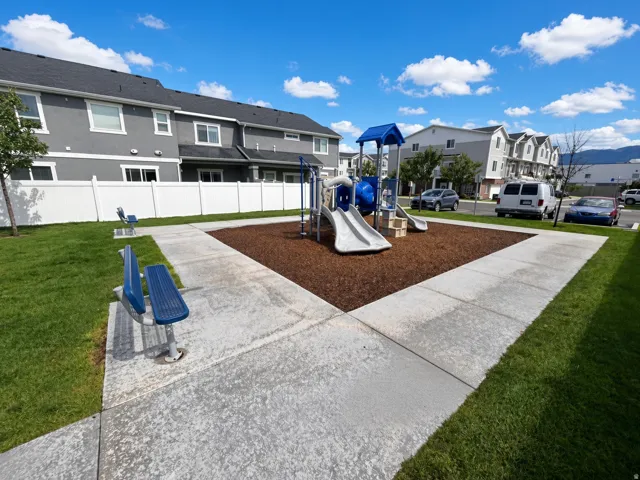 Community playground featuring a slide and climbing structure with a wood chip base