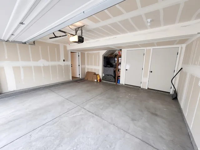 Concrete flooring with a finished curb, automatic garage door opener, and two interior access doors