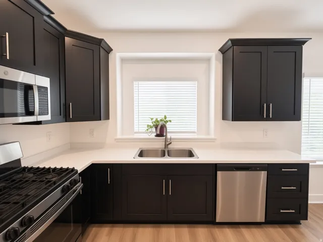 Kitchen featuring dark shaker-style cabinetry, stainless steel appliances, a double basin sink, and light countertops