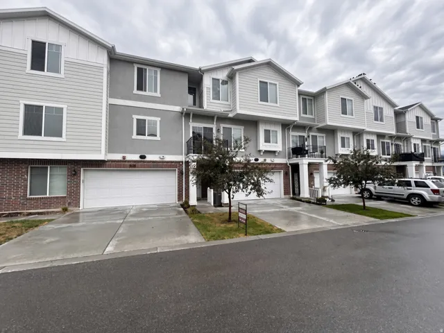 Multi-level townhome with a brick and siding exterior, private two-car garage, and concrete driveway