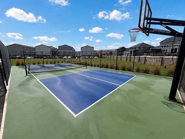 Recreational court featuring multiple pickleball courts with nets and an adjacent basketball hoop