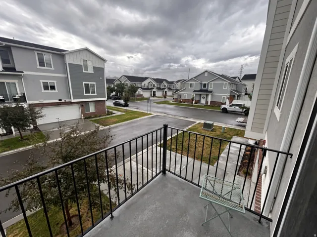 Private balcony with metal railing, stucco exterior, and adjacent townhome architecture