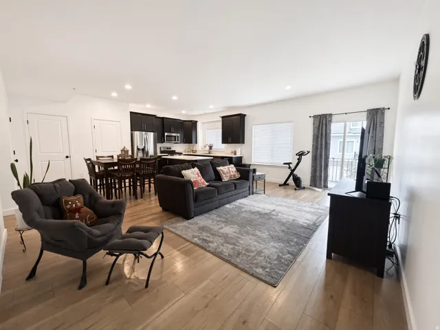 Open-concept living area with wood-finish flooring, recessed lighting, and a sliding glass door